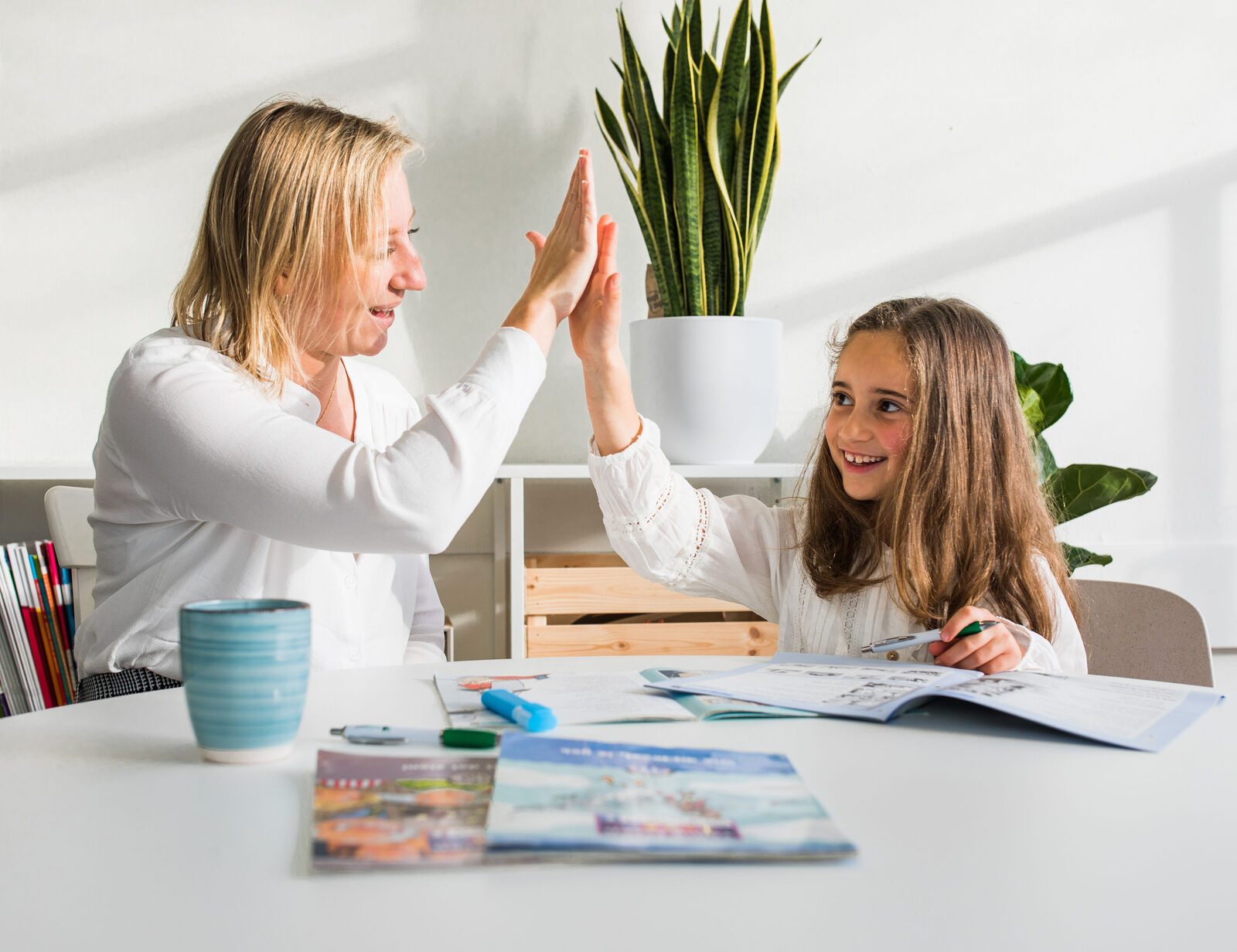 Begeleider en leerling geven elkaar een high five op school